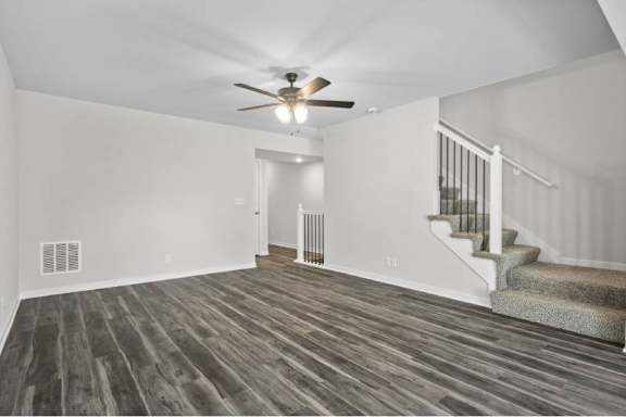 A room with a staircase and a ceiling fan.