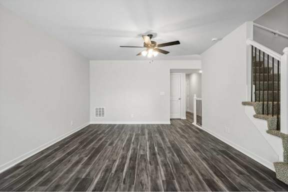 A room with a ceiling fan and wooden flooring.