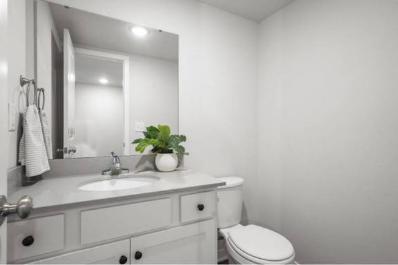 A bathroom with a toilet, sink, and mirror.