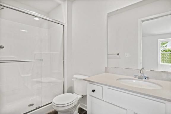 A white bathroom with a toilet, sink, and shower.