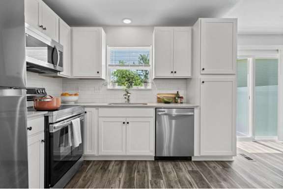 A modern kitchen with white cabinets and stainless steel appliances.