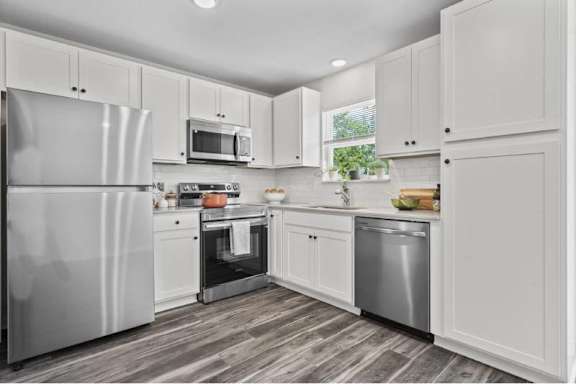 A modern kitchen with white cabinets and stainless steel appliances.
