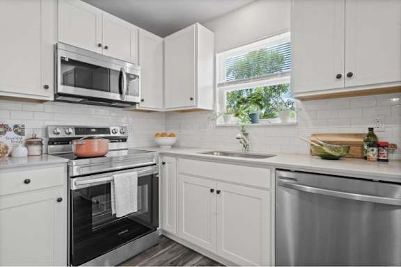 A kitchen with white cabinets and a stainless steel sink.