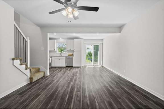A spacious room with a staircase and a ceiling fan.