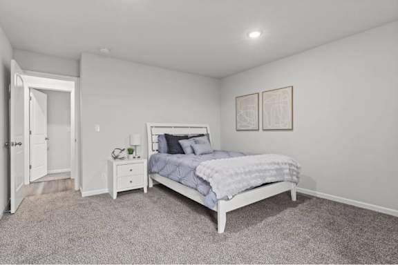A bedroom with a bed, nightstand, and two framed pictures on the wall.