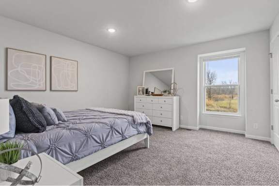 A bedroom with a bed, dresser, and window.