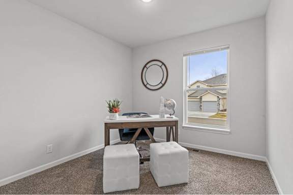 A room with a table, two stools, and a window showing a house.
