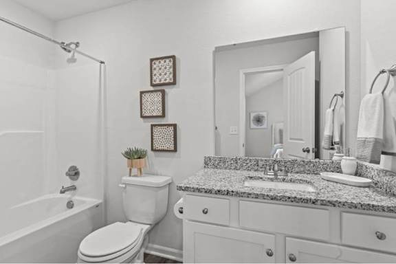 A white bathroom with a toilet, sink, and mirror.