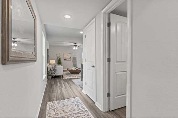 A hallway with a rug and a white door.