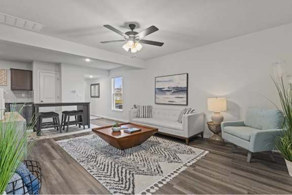 A living room with a white couch, a coffee table, and a ceiling fan.