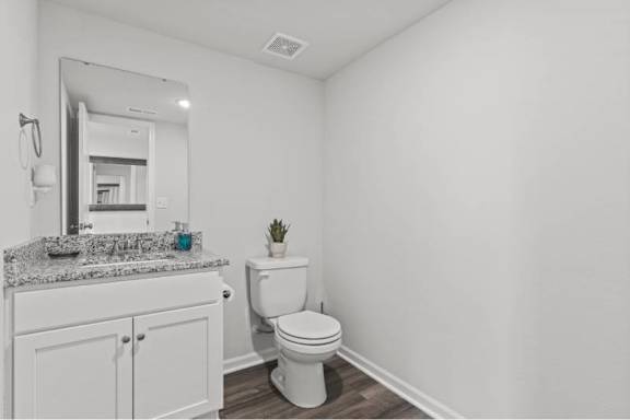 A white bathroom with a toilet, sink, and mirror.