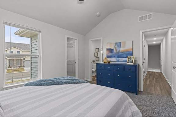 A bedroom with a blue bedspread and a blue dresser.