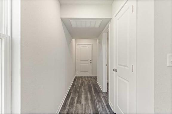A long hallway with white walls and wood flooring.