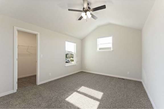 A room with a ceiling fan and two windows.