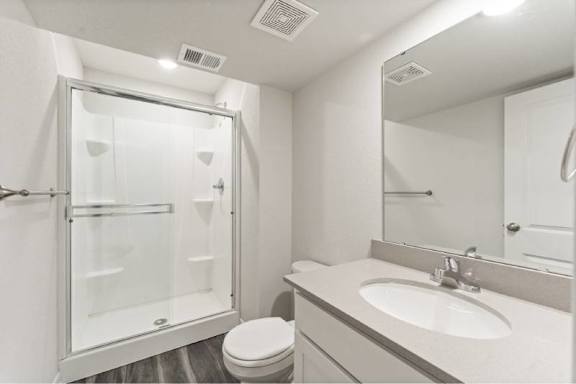 A white bathroom with a toilet, sink, and shower.