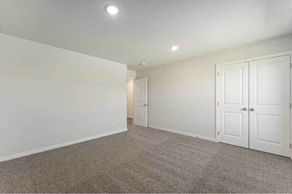 A room with a carpeted floor and two white doors.