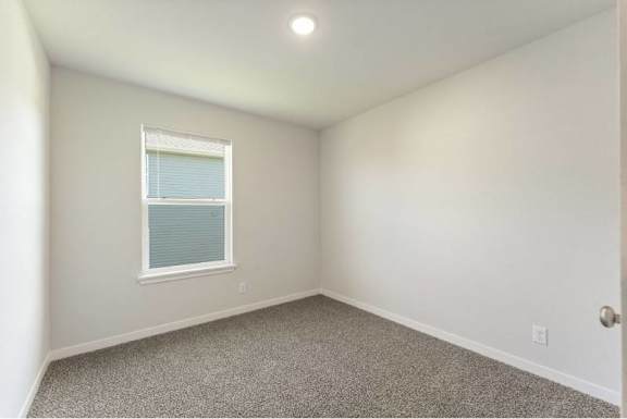 A room with a window and carpeted floor.