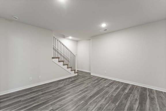 A room with a wooden floor and a staircase.