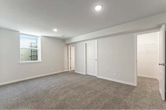 A spacious room with a carpeted floor and white walls.