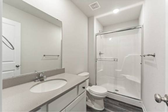 A white bathroom with a sink, toilet, and shower.