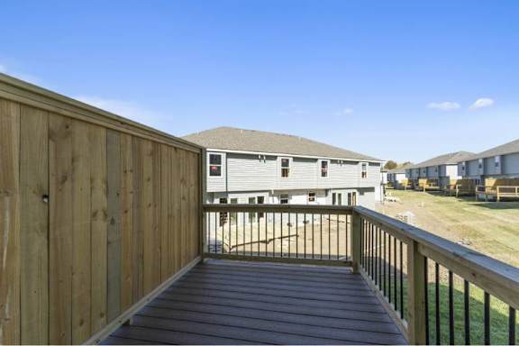 A wooden deck overlooks a grassy area with houses in the distance.