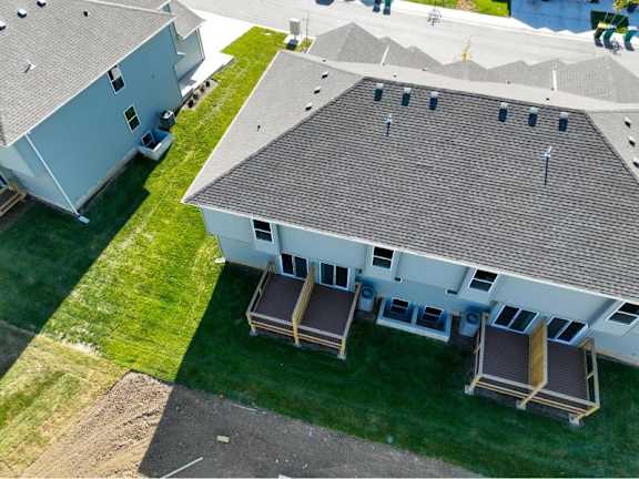 A house with a grey roof and a white exterior is shown from an aerial perspective.