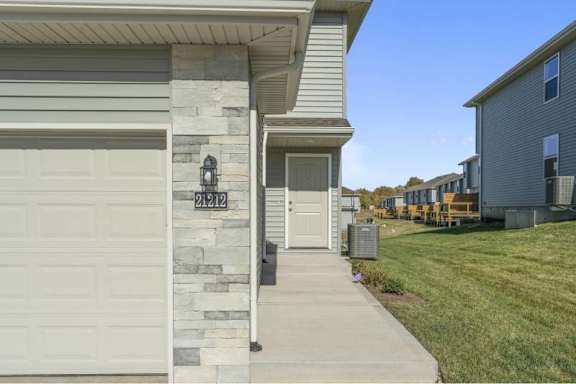 A house with a white garage door and a stone pillar.