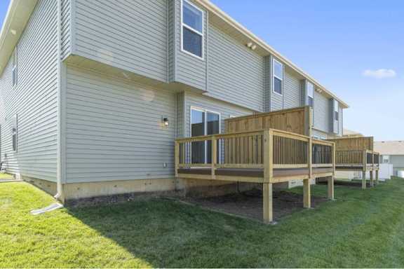 A grey house with a wooden deck in front.
