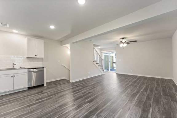 A spacious room with wooden flooring and white walls.