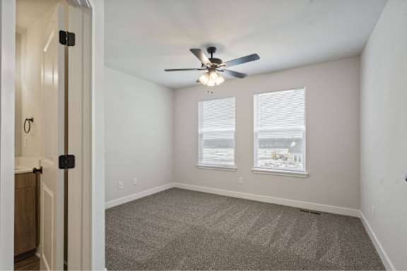 A room with a ceiling fan and carpeted floor.
