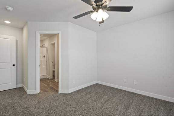 A room with a ceiling fan and carpeted floor.