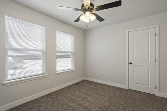 A room with a ceiling fan and carpeted floor.