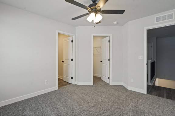 A room with a ceiling fan and carpeted floor.