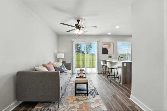 A well-lit bedroom with a grey bed and a ceiling fan.