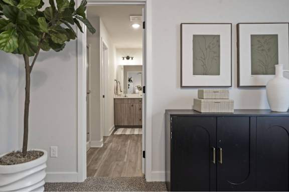A black cabinet with a white vase on top and two framed pictures on the wall.