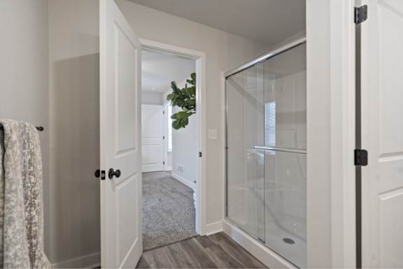 A bathroom with a glass shower door and a white door.