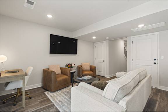 A living room with a couch, chairs, and a television.