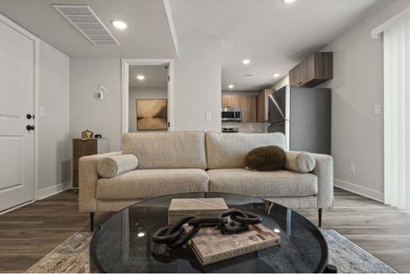 A modern living room with a glass coffee table and a beige couch.