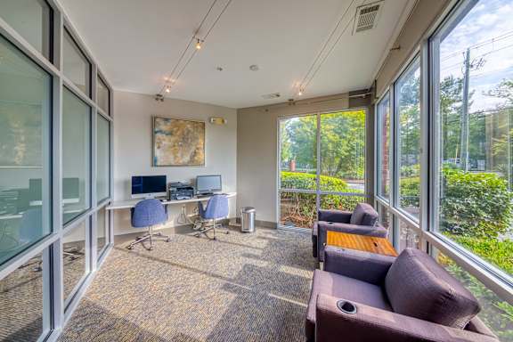 A room with a desk, chairs, and a couch with a view of the outside.