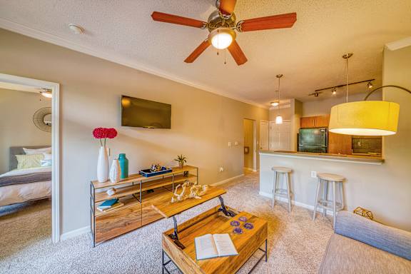 A living room with a ceiling fan and a flat screen TV mounted on the wall.