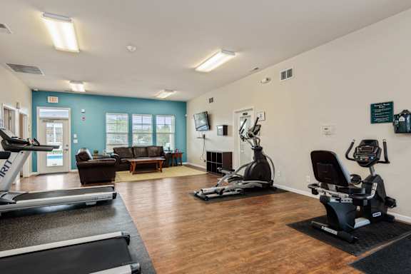 A gym with treadmills, elliptical machines, and a couch.