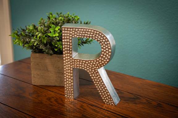 A decorative letter R is on a table.