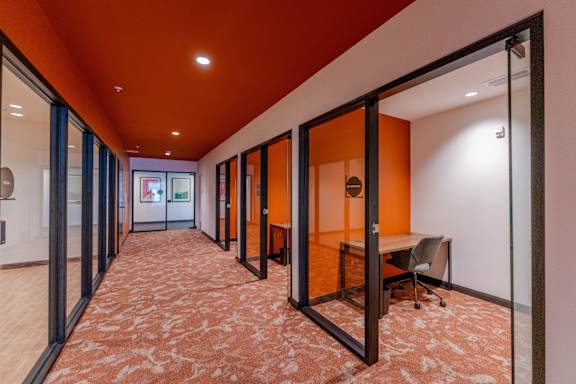 A hallway with orange walls and a carpeted floor.