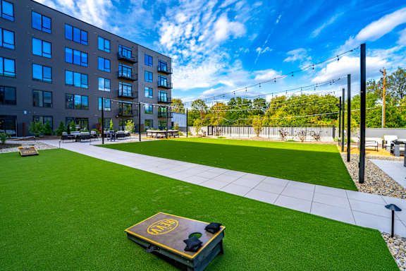 A modern building with a green lawn in front and a bench with a logo on it.