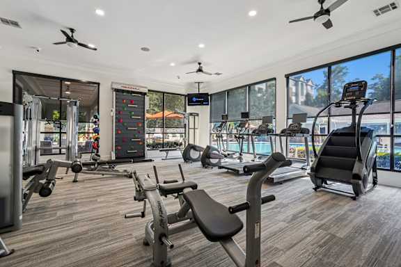 A gym with a variety of equipment including treadmills, weights, and exercise machines.
