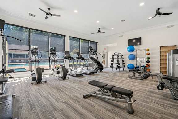 A gym with a variety of equipment including treadmills, weights, and exercise machines.