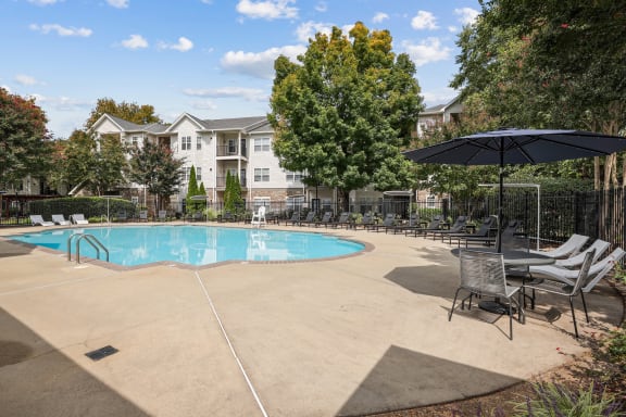 a swimming pool with chairs and umbrellas at the enclave at woodbury apartments