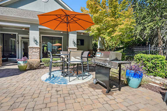 A patio with a table, chairs, and an umbrella.