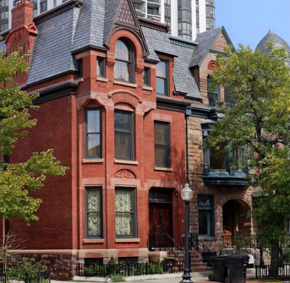 A red brick Victorian style house with a black iron fence.