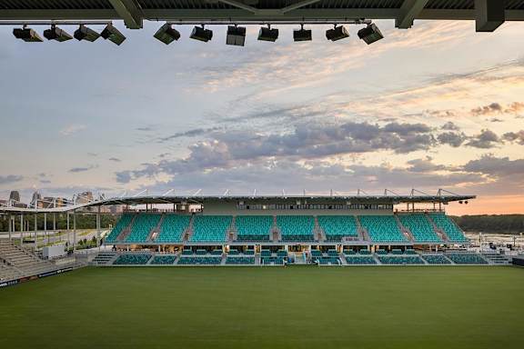 A large stadium with green seats and a clear sky above.